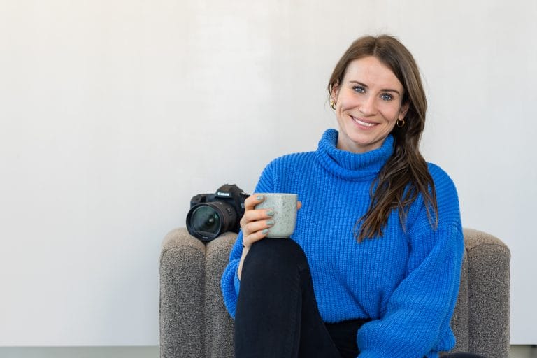 Bild der Gründerin Magdalena Piller, die in die Kamera lächelt und einen blauen Pullover trägt. Sie sitzt leger vor einer Couch und hat eine Kaffeetasse in der Hand.