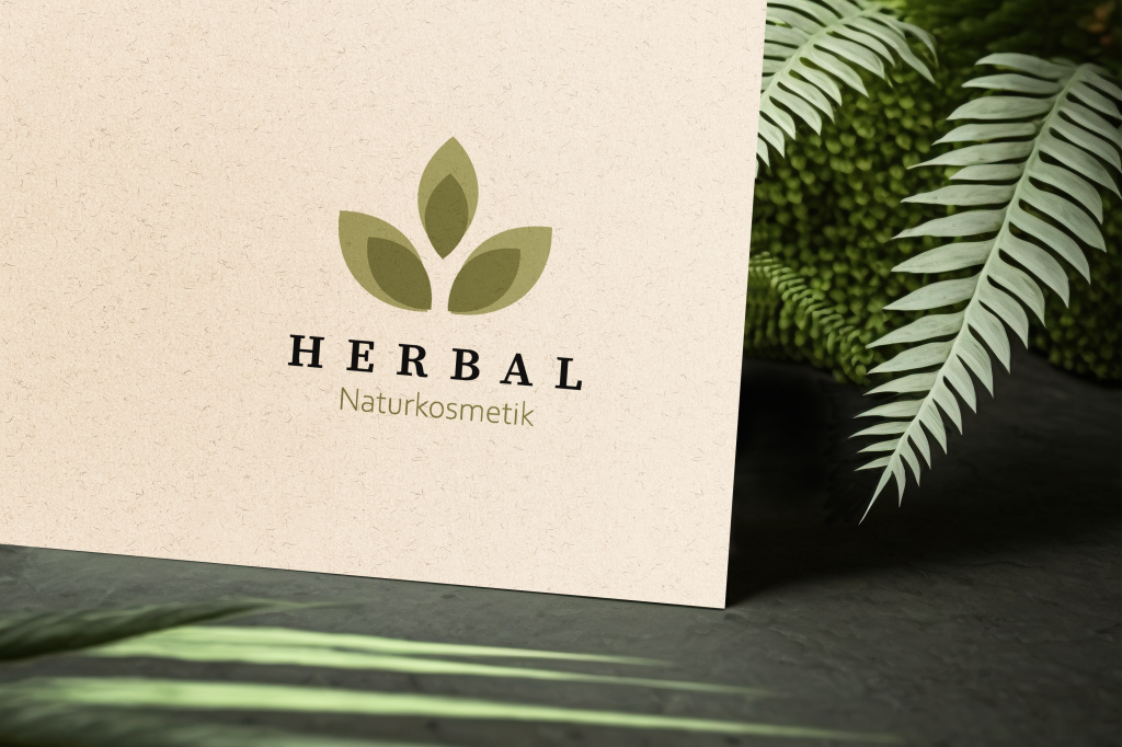 Referenzbild des Herbal Naturkosmetik - Logodesigns auf Naturkarton mit Pflanzen im Hintergrund.